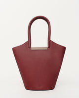 Small garden tote bag in burgundy with sculptural silhouette and walnut wood handle.