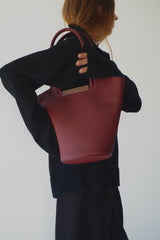 Woman holding a small garden tote bag in burgundy, showcasing its stylish design and quality craftsmanship.