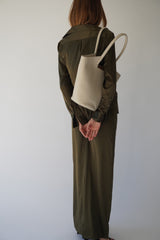 Woman wearing a small garden tote bag in cream, styled with an elegant olive-green outfit.