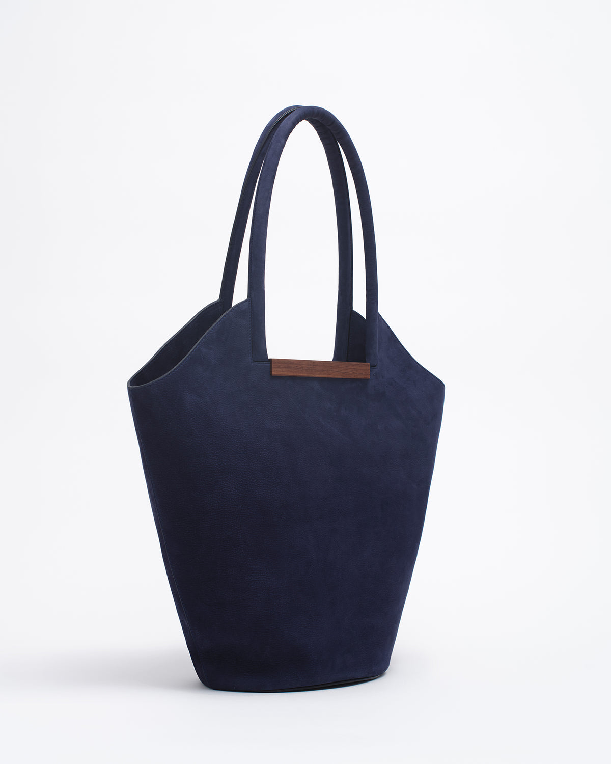 Garden tote bag in dark blue with wooden crafted handle, showcasing a sculptural design and soft suede texture.