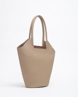 Garden tote bag in beige with wooden crafted handle, showcasing a sculptural design and soft suede texture.
