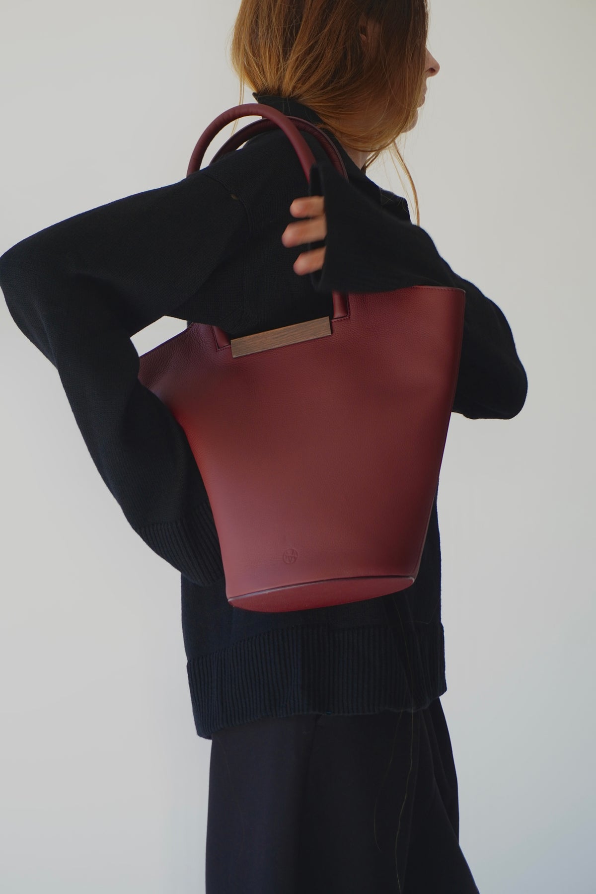 Woman holding a small garden tote bag in burgundy, showcasing its stylish design and quality craftsmanship.